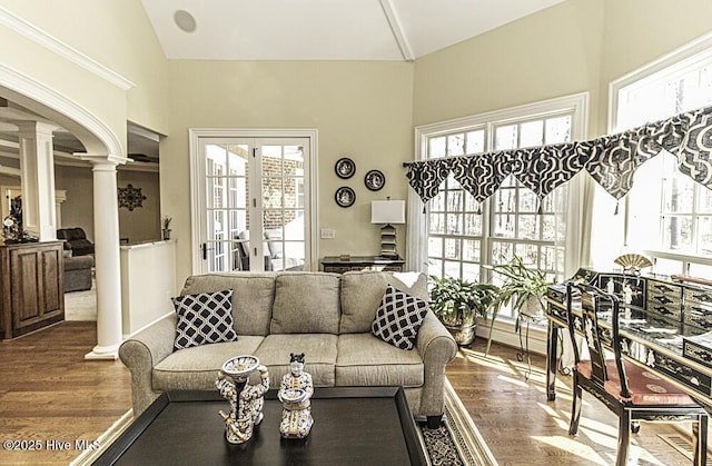 living room with lofted ceiling, hardwood / wood-style flooring, and decorative columns