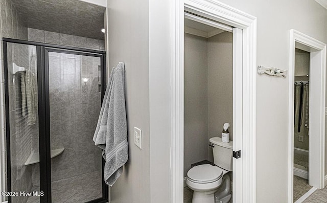 bathroom with toilet, an enclosed shower, and tile patterned flooring