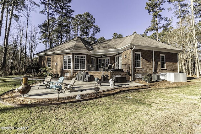 rear view of house with a patio area, a yard, and central AC