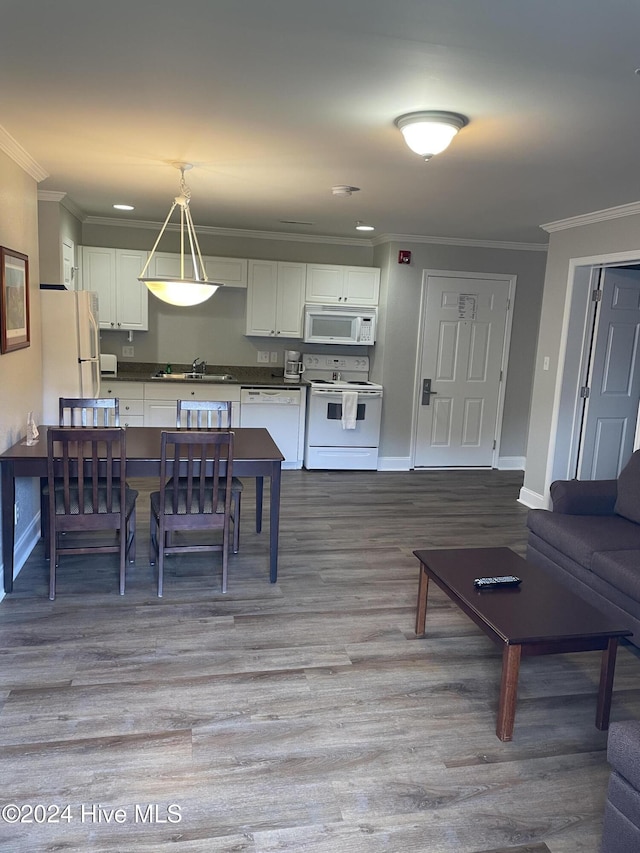 kitchen featuring white appliances, white cabinetry, hanging light fixtures, and sink