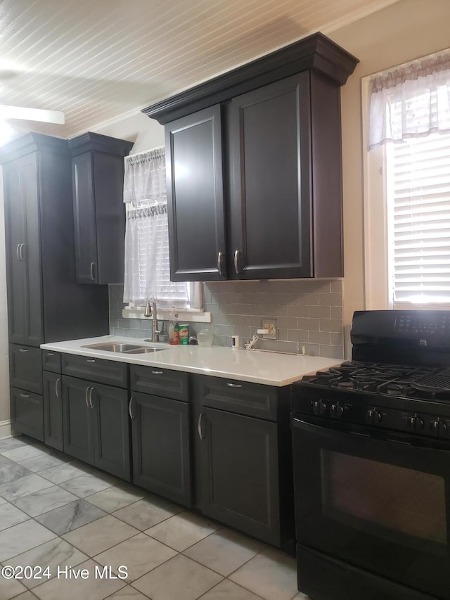 kitchen with black gas stove, backsplash, ornamental molding, and sink