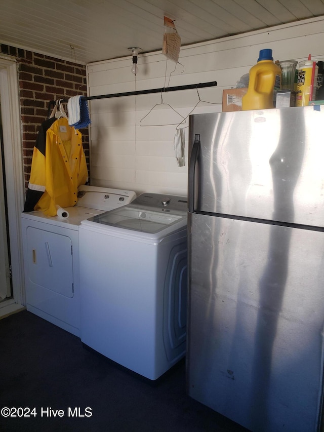 laundry area with washer and clothes dryer and brick wall