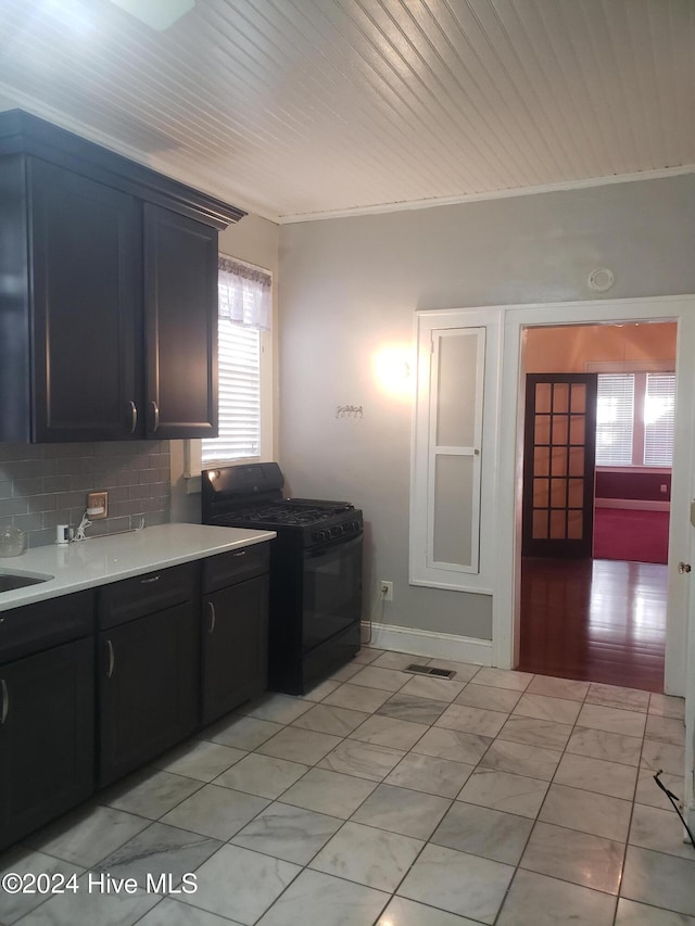 kitchen featuring tasteful backsplash, crown molding, sink, and black range oven