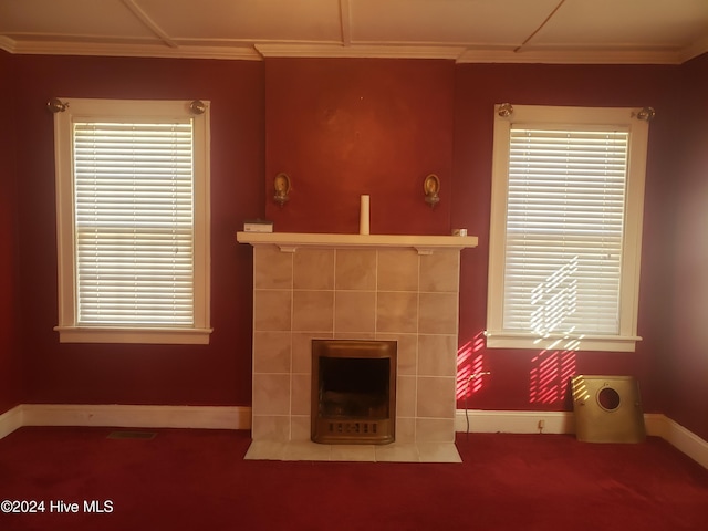 unfurnished living room featuring a tile fireplace, crown molding, and carpet