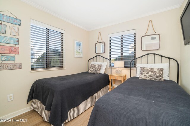 bedroom with light wood-type flooring and crown molding