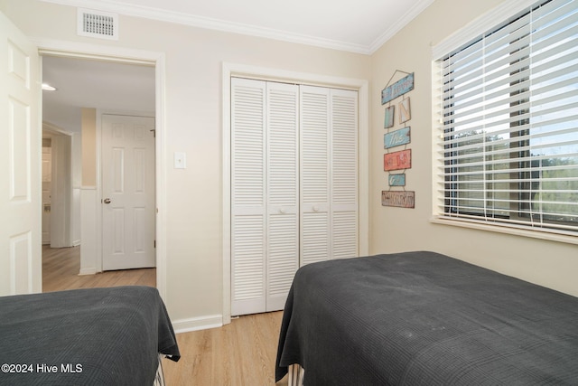 bedroom with crown molding, a closet, and light hardwood / wood-style flooring