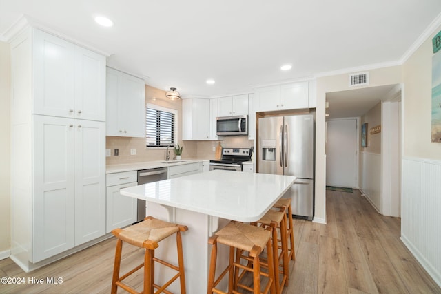 kitchen with a breakfast bar area, white cabinetry, light hardwood / wood-style flooring, and stainless steel appliances