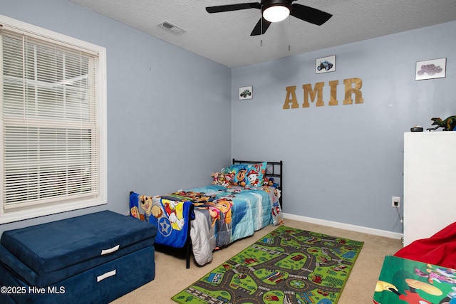 carpeted bedroom with ceiling fan and a textured ceiling