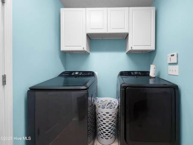 washroom with washing machine and clothes dryer, cabinets, and a textured ceiling