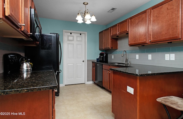 kitchen featuring dark stone counters, black appliances, sink, decorative light fixtures, and an inviting chandelier