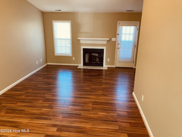 unfurnished living room with dark hardwood / wood-style flooring and a healthy amount of sunlight