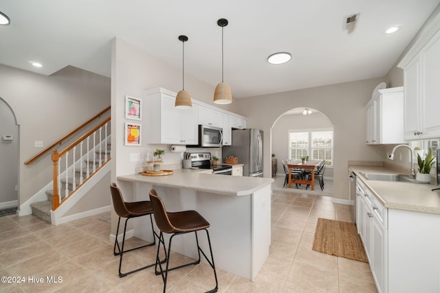 kitchen with stainless steel appliances, sink, decorative light fixtures, white cabinets, and light tile patterned flooring