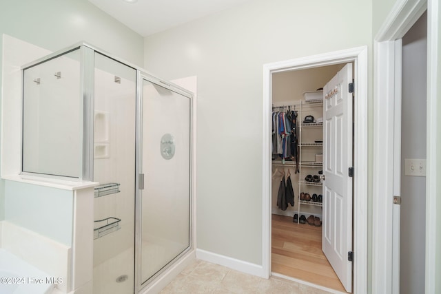 bathroom with a shower with door and tile patterned flooring