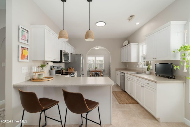 kitchen featuring sink, stainless steel appliances, kitchen peninsula, decorative light fixtures, and white cabinets