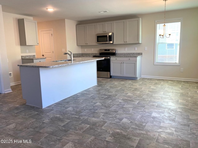 kitchen with appliances with stainless steel finishes, decorative light fixtures, sink, gray cabinetry, and light stone counters