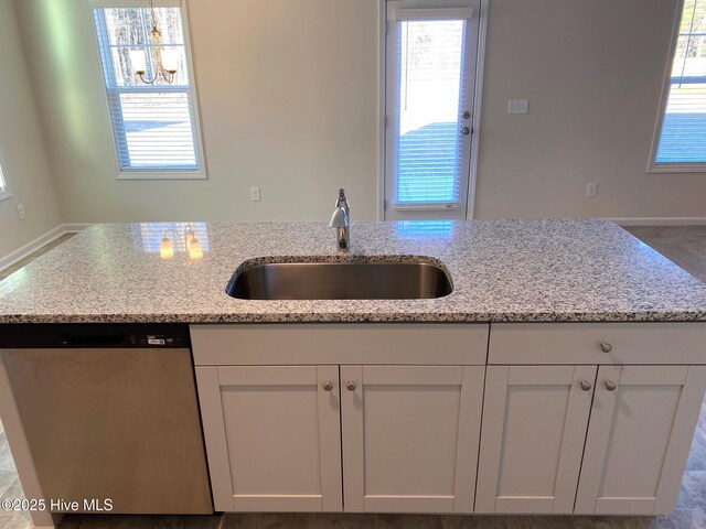 kitchen with stainless steel dishwasher, light stone countertops, sink, and white cabinets