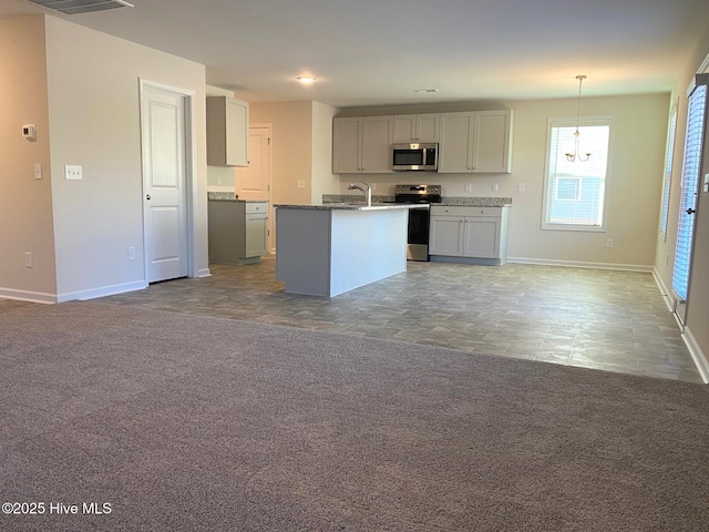 kitchen featuring appliances with stainless steel finishes, gray cabinetry, hanging light fixtures, carpet, and a kitchen island with sink