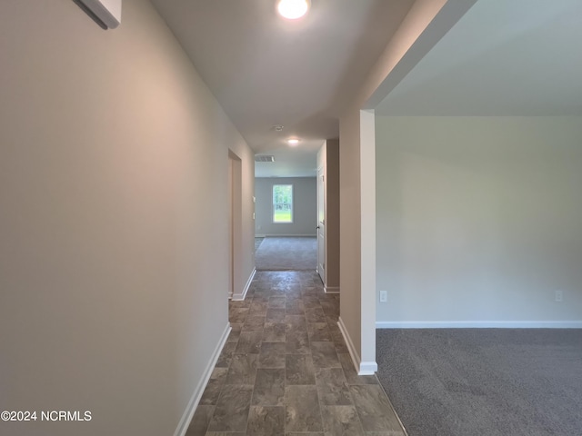 hallway with dark carpet and a wall unit AC