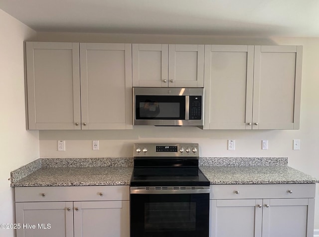 kitchen featuring light stone counters, range with electric stovetop, and white cabinetry