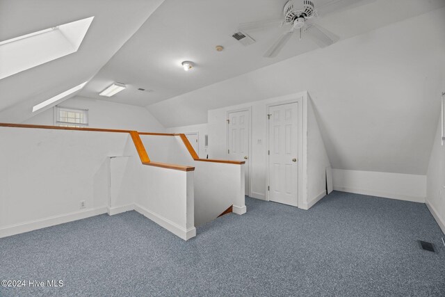 additional living space featuring carpet, lofted ceiling with skylight, and ceiling fan