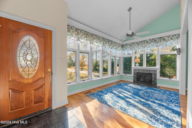 foyer featuring a tile fireplace, dark hardwood / wood-style floors, vaulted ceiling, and ceiling fan