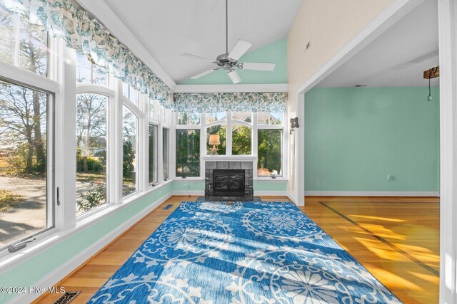 sunroom with ceiling fan, a fireplace, and vaulted ceiling