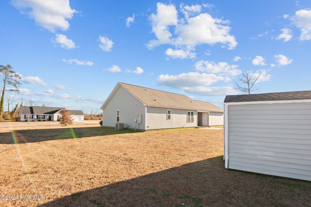 rear view of property featuring central AC unit and a storage shed