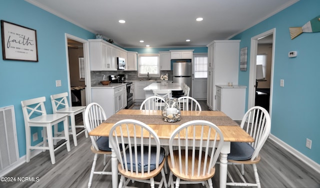 dining space featuring crown molding, light wood-type flooring, and sink