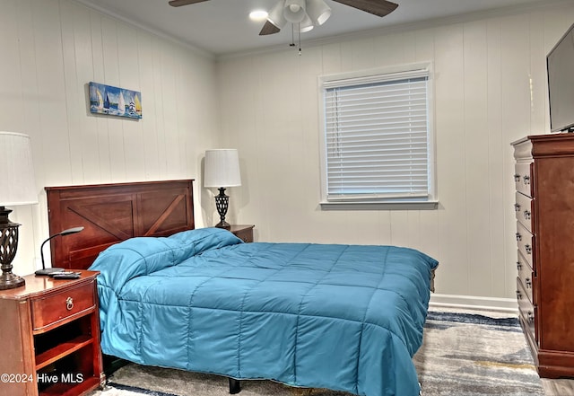 bedroom featuring ceiling fan, ornamental molding, and wooden walls