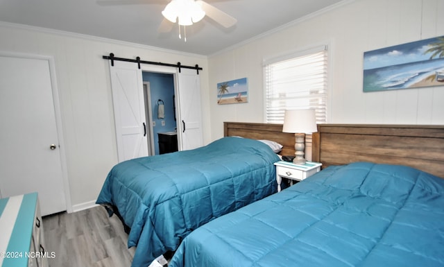 bedroom featuring ceiling fan, a barn door, light wood-type flooring, and crown molding