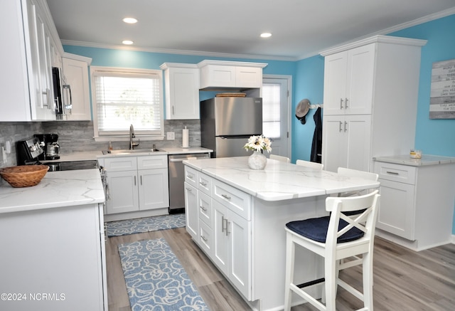 kitchen featuring a center island, sink, appliances with stainless steel finishes, light hardwood / wood-style floors, and white cabinetry