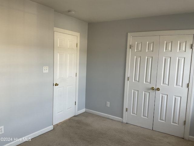 unfurnished bedroom with light colored carpet and a closet