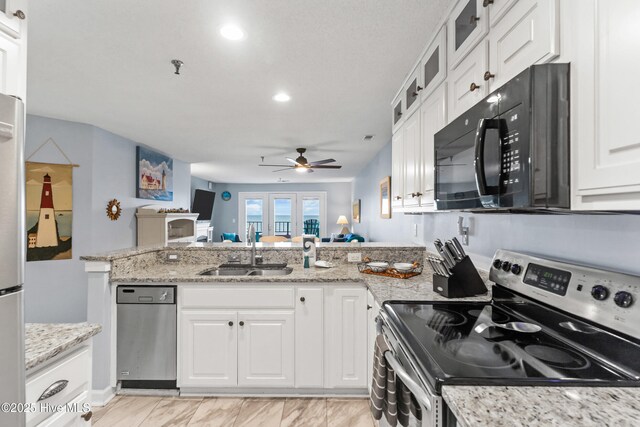 kitchen featuring sink, stainless steel range with electric cooktop, white cabinets, and light stone countertops