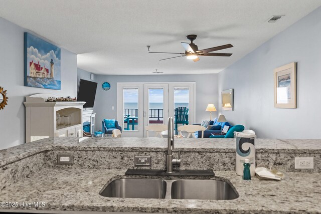 kitchen with sink, white cabinetry, ceiling fan, light stone countertops, and appliances with stainless steel finishes