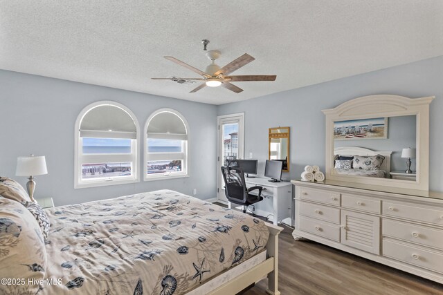 bedroom featuring dark hardwood / wood-style flooring, a textured ceiling, and ceiling fan