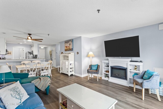 living room featuring a textured ceiling, hardwood / wood-style floors, and ceiling fan