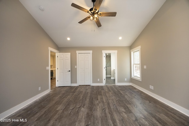 unfurnished bedroom with vaulted ceiling, dark wood-type flooring, ensuite bathroom, and a closet