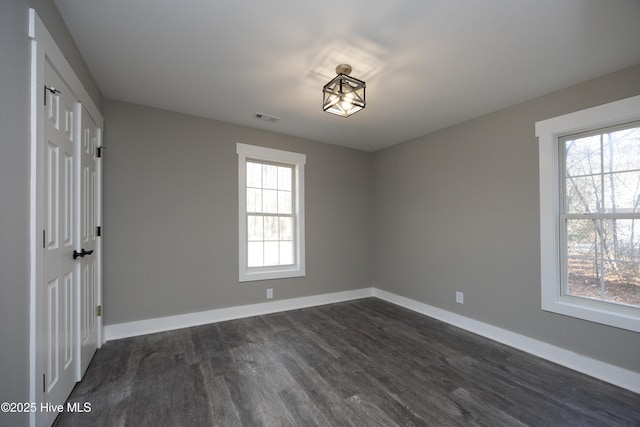 spare room featuring a wealth of natural light and dark hardwood / wood-style floors