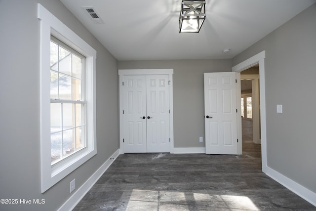 unfurnished bedroom with multiple windows and dark hardwood / wood-style floors