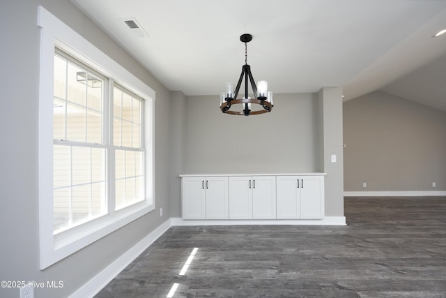 unfurnished dining area with an inviting chandelier, lofted ceiling, and dark hardwood / wood-style floors