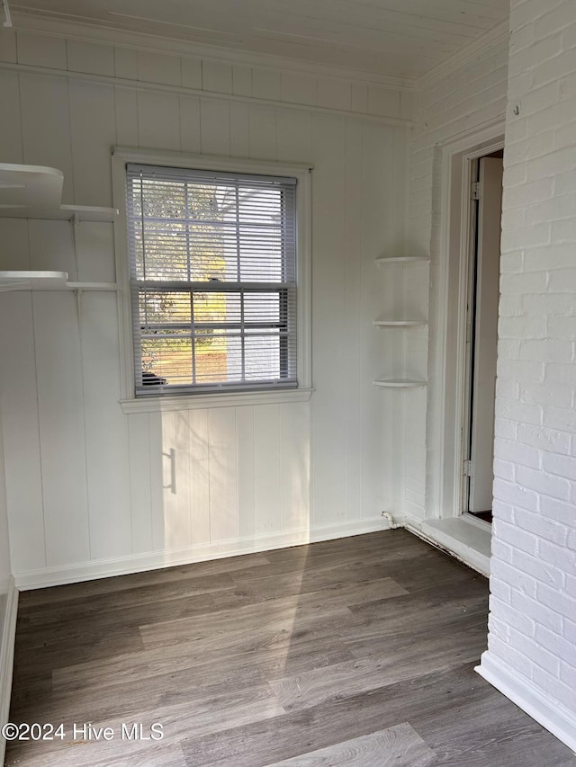 empty room featuring wood-type flooring and brick wall