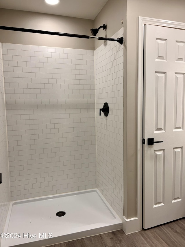 bathroom with tiled shower and hardwood / wood-style flooring