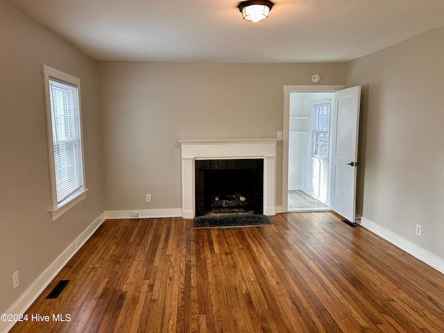 unfurnished living room with a fireplace, plenty of natural light, and wood-type flooring