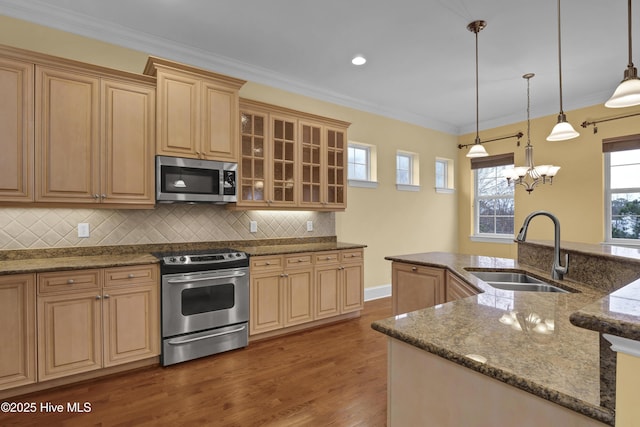 kitchen featuring pendant lighting, sink, crown molding, a notable chandelier, and stainless steel appliances