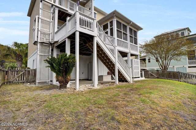 back of property featuring a lawn, a patio area, and a sunroom