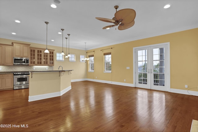 kitchen featuring decorative backsplash, stainless steel appliances, ceiling fan, hanging light fixtures, and a breakfast bar area