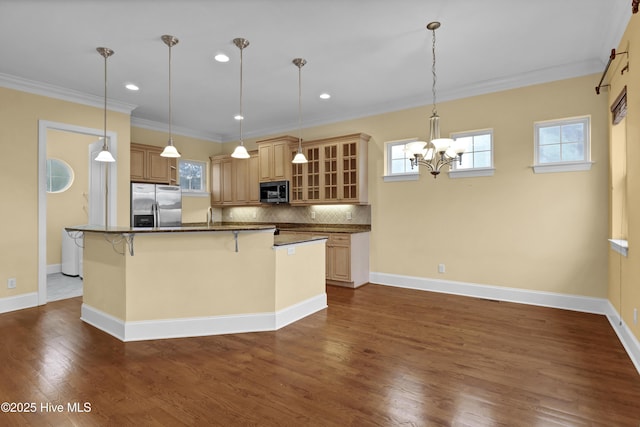 kitchen featuring an inviting chandelier, decorative light fixtures, a breakfast bar, appliances with stainless steel finishes, and ornamental molding