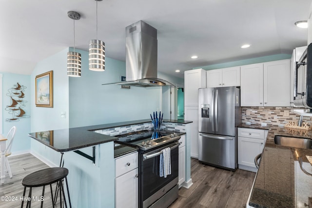 kitchen featuring white cabinets, hanging light fixtures, wall chimney range hood, and appliances with stainless steel finishes