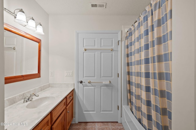 bathroom with tile patterned flooring, vanity, shower / bath combo, and a textured ceiling