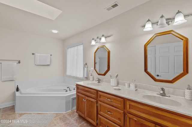 bathroom featuring tile patterned flooring, vanity, tiled bath, and a skylight